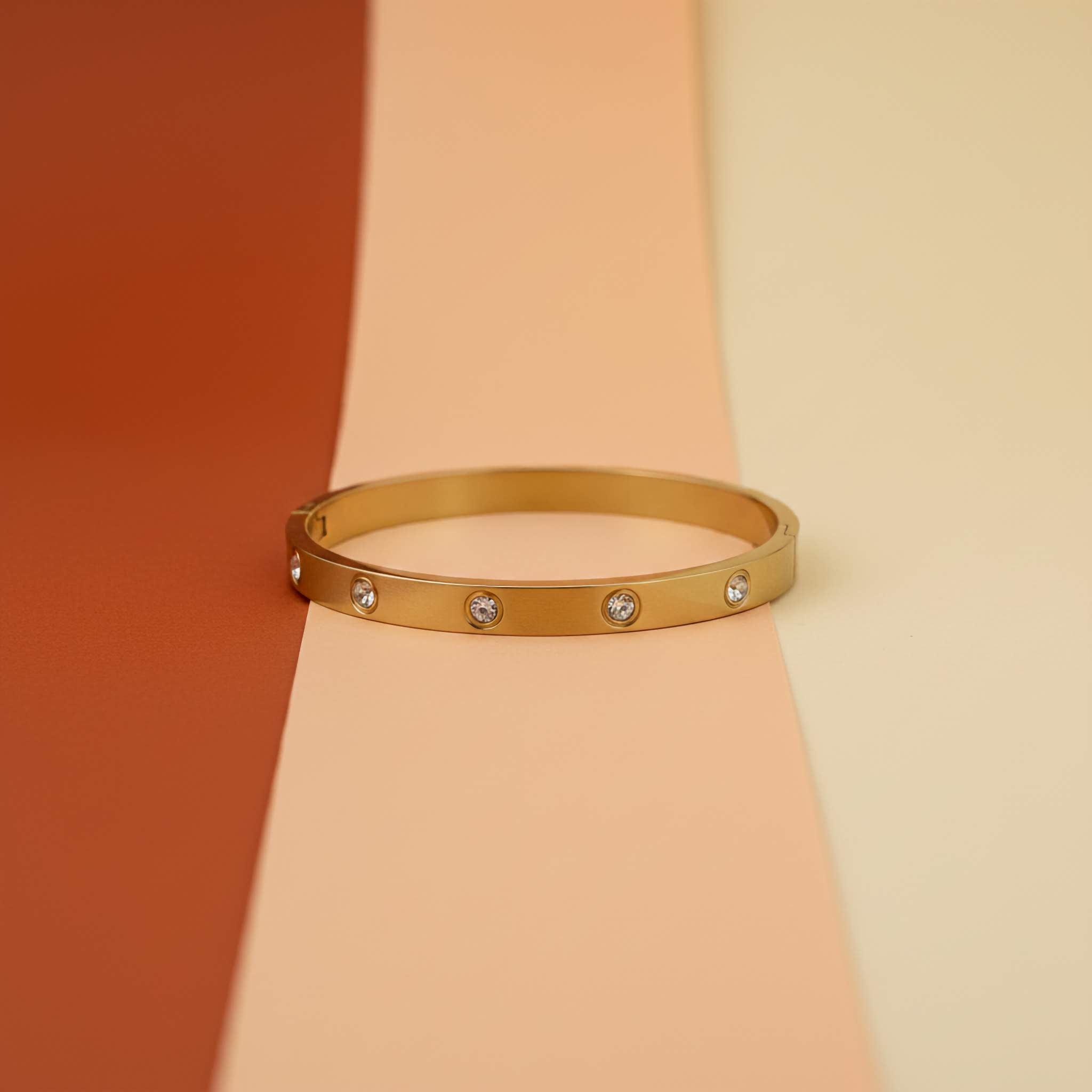 Stylish everyday fashion jewelry gold bangle bracelet with gems on colorful background.