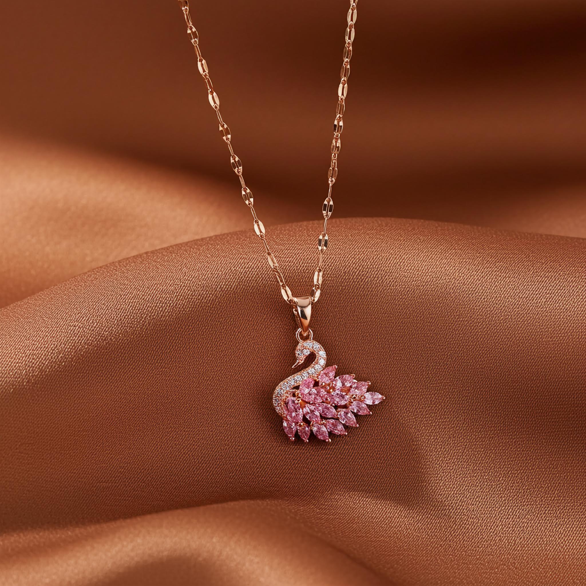 Affordable Swarovski crystal jewelry featuring a pink swan pendant on a delicate chain, displayed on satin fabric.