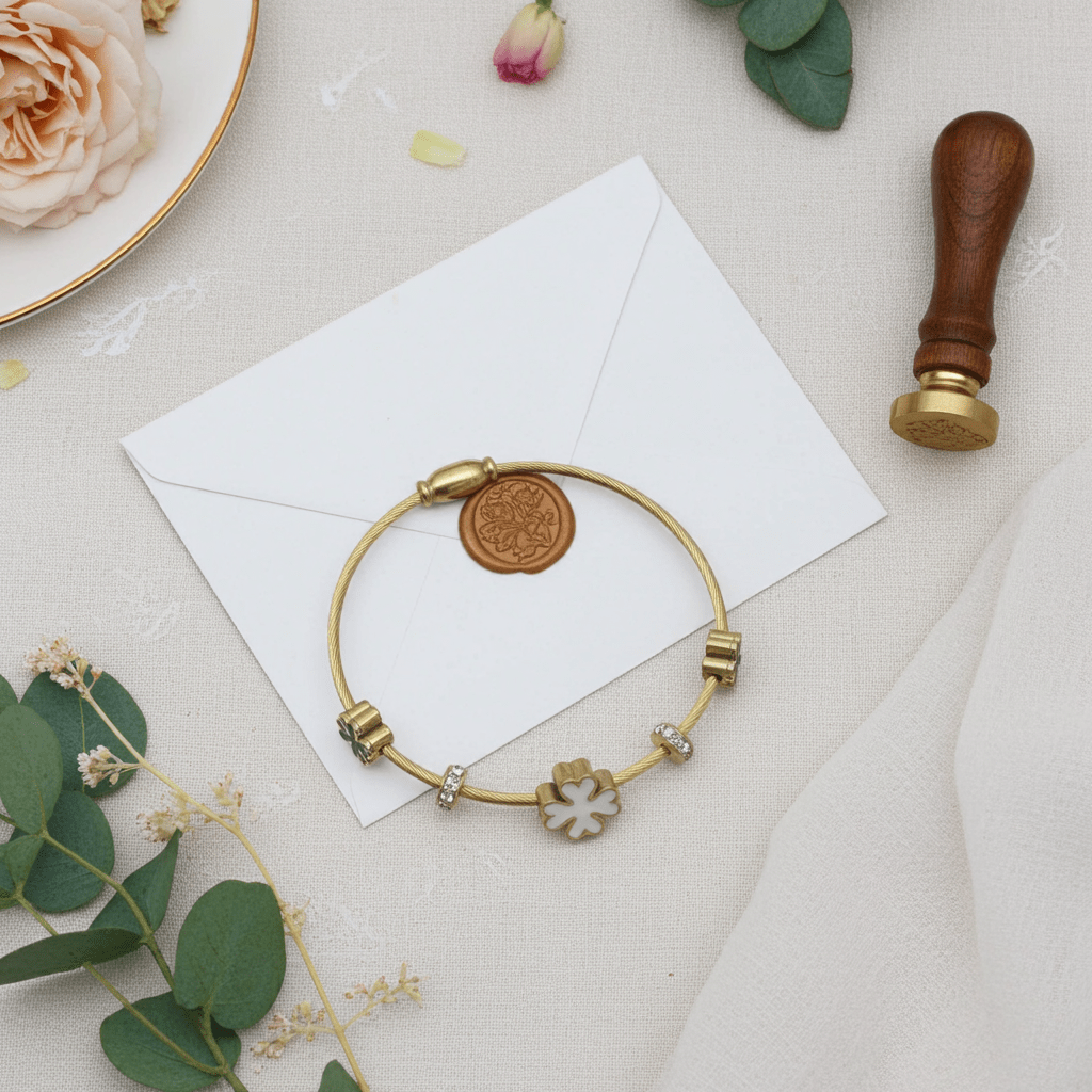 3 leaf charm bracelet with 18k gold plating on a white paper