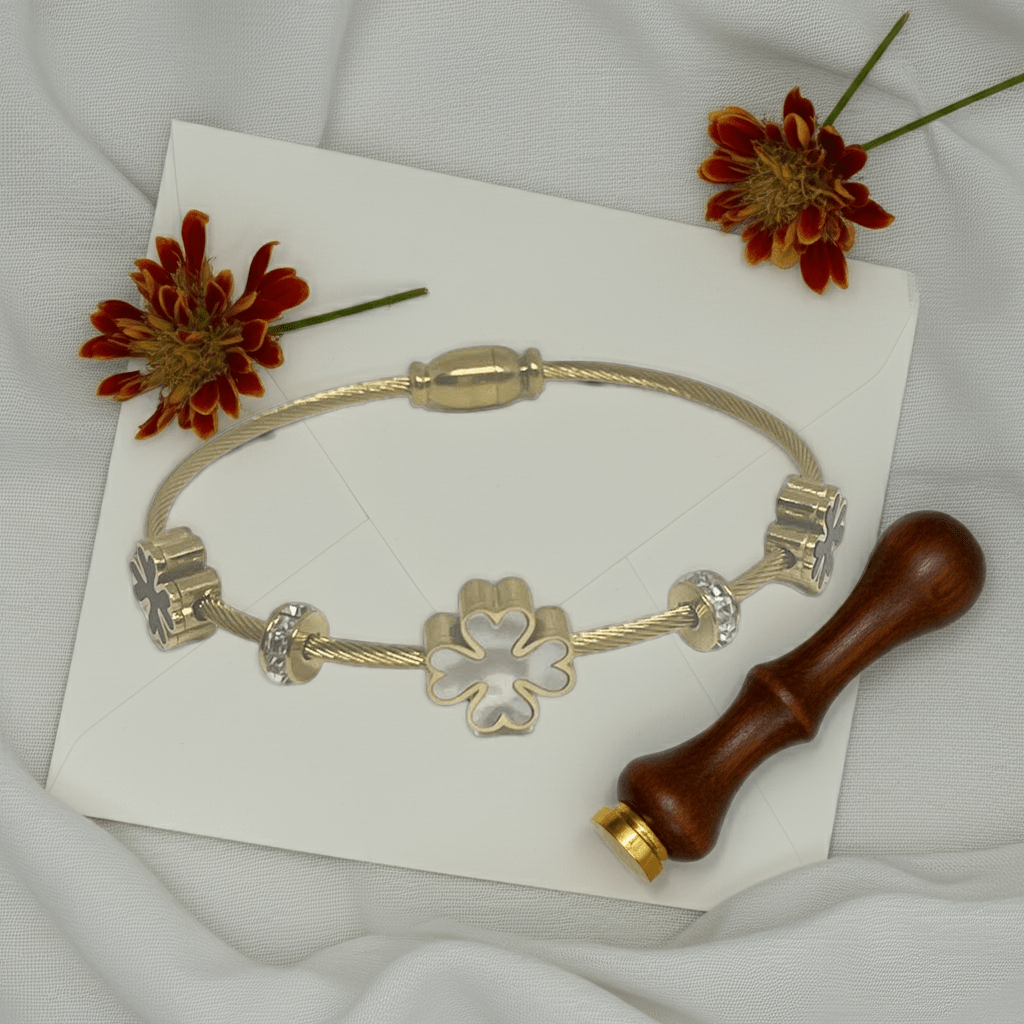 3 leaf charm bracelet with 18k gold plating on a white wedding card.