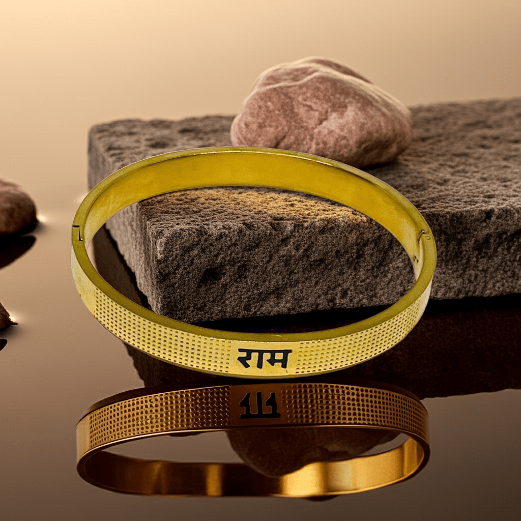 Gold bangles with engraved Ram on a reflective surface with stones in the background