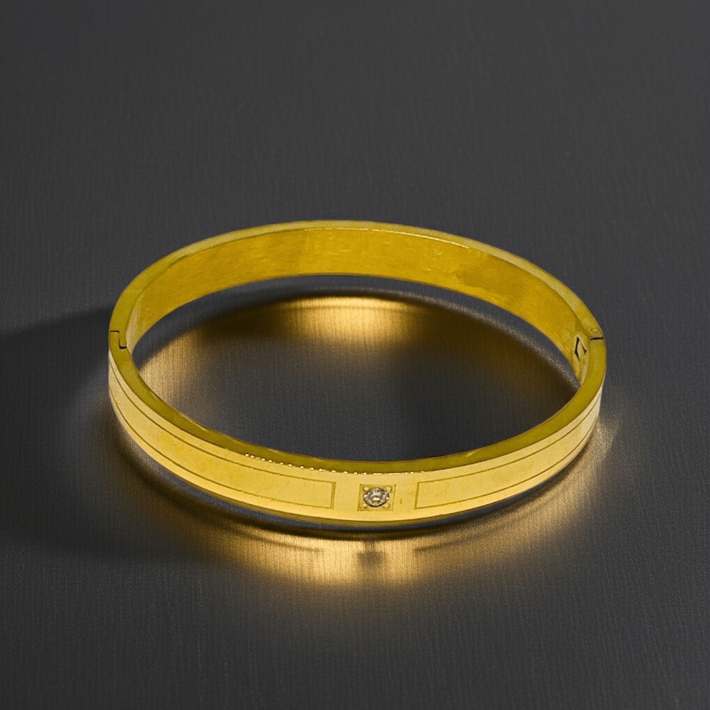 Gold bracelet on a dark reflective surface