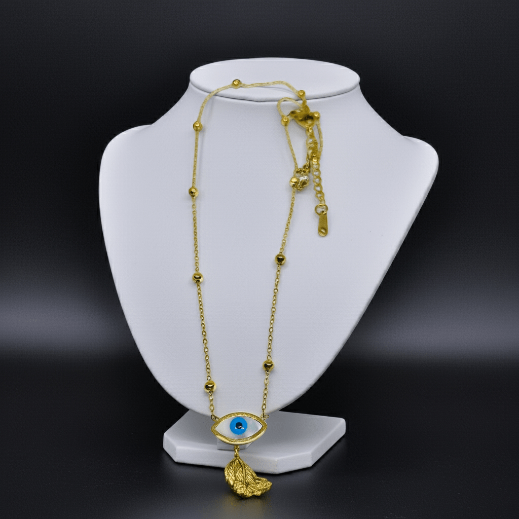 Gold necklace with an eye design on a white bust against a black background