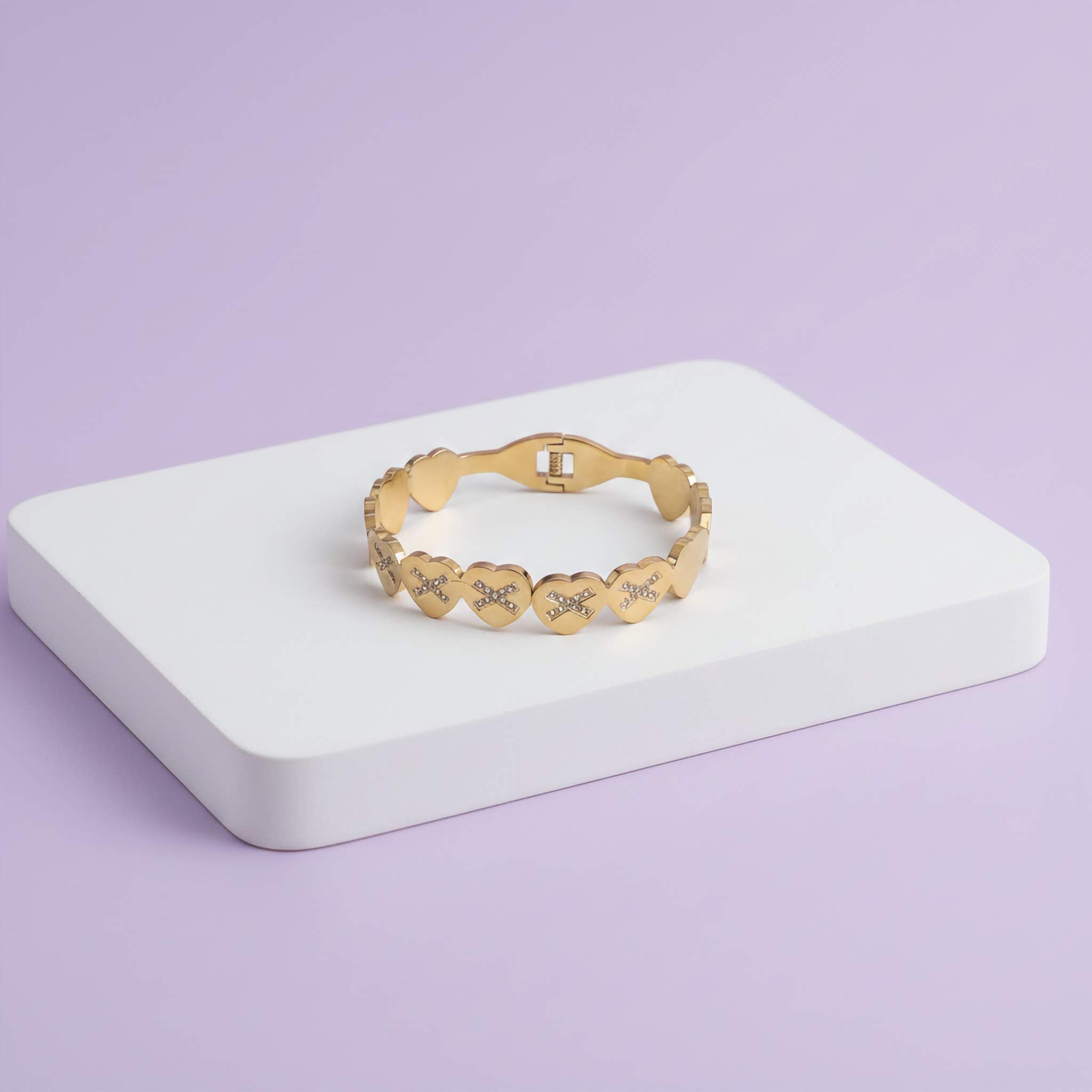 18k Gold bracelet with heart designs on a white stand against a light purple background