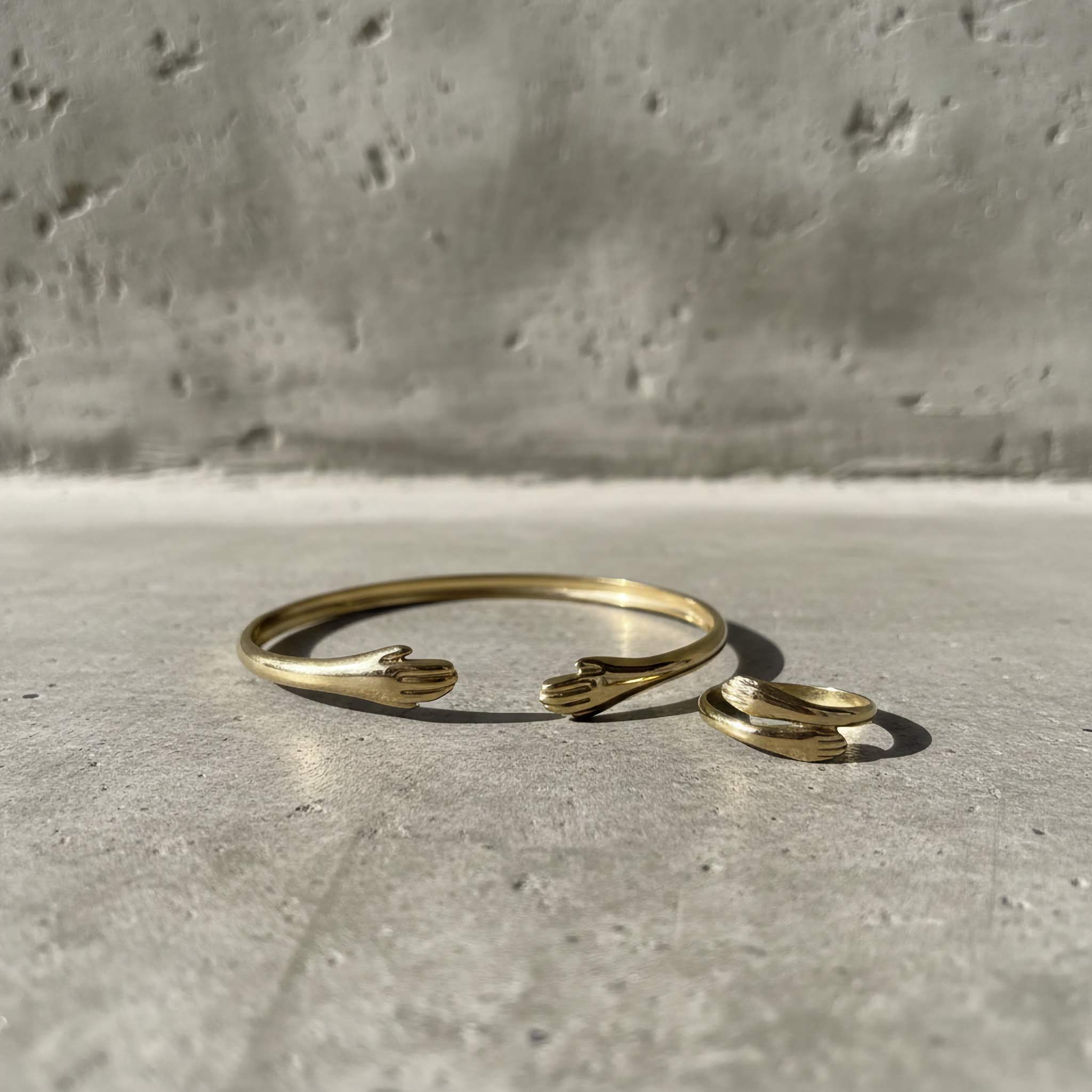 18k Gold plated bracelet and ring set on a concrete surface with a gray background