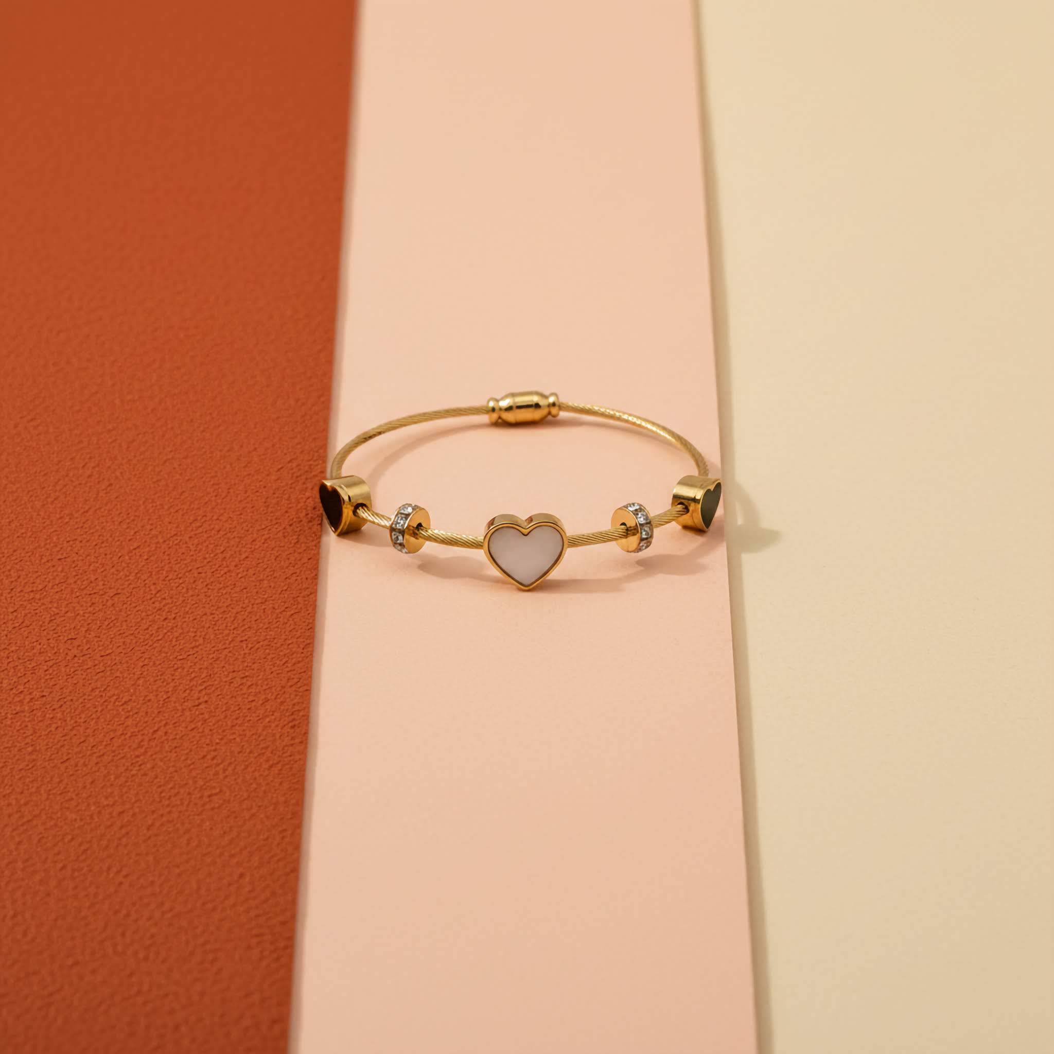 18k Gold plated bracelet with a heart charm duel tone on a pink and orange gradient background