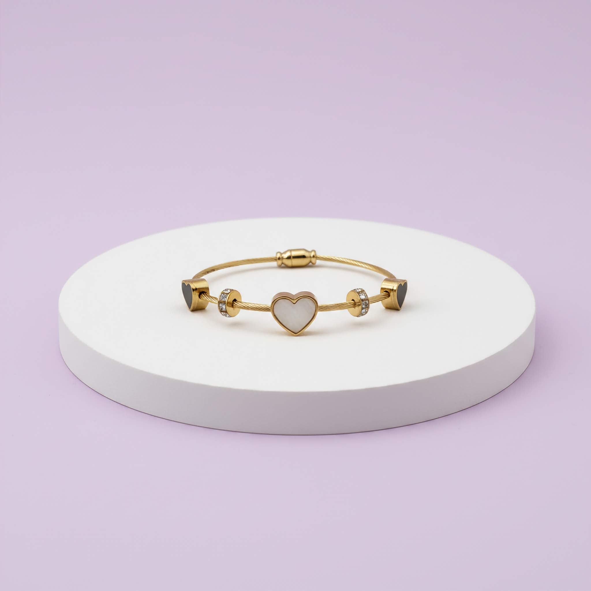 18k Gold plated bracelet with a heart charm on a white stand against a light purple background