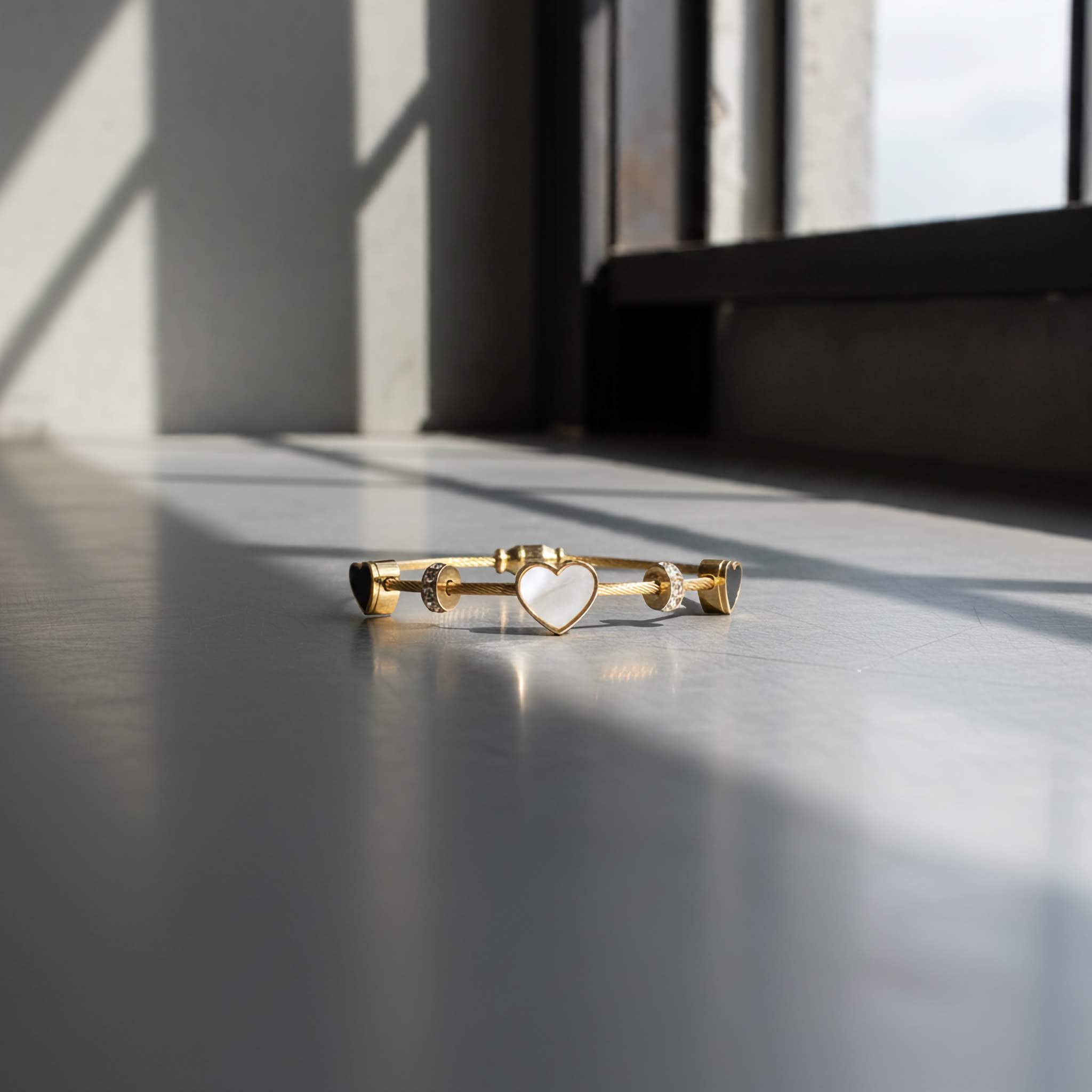 18k Gold plated bracelet with black and white heart design on a reflective surface