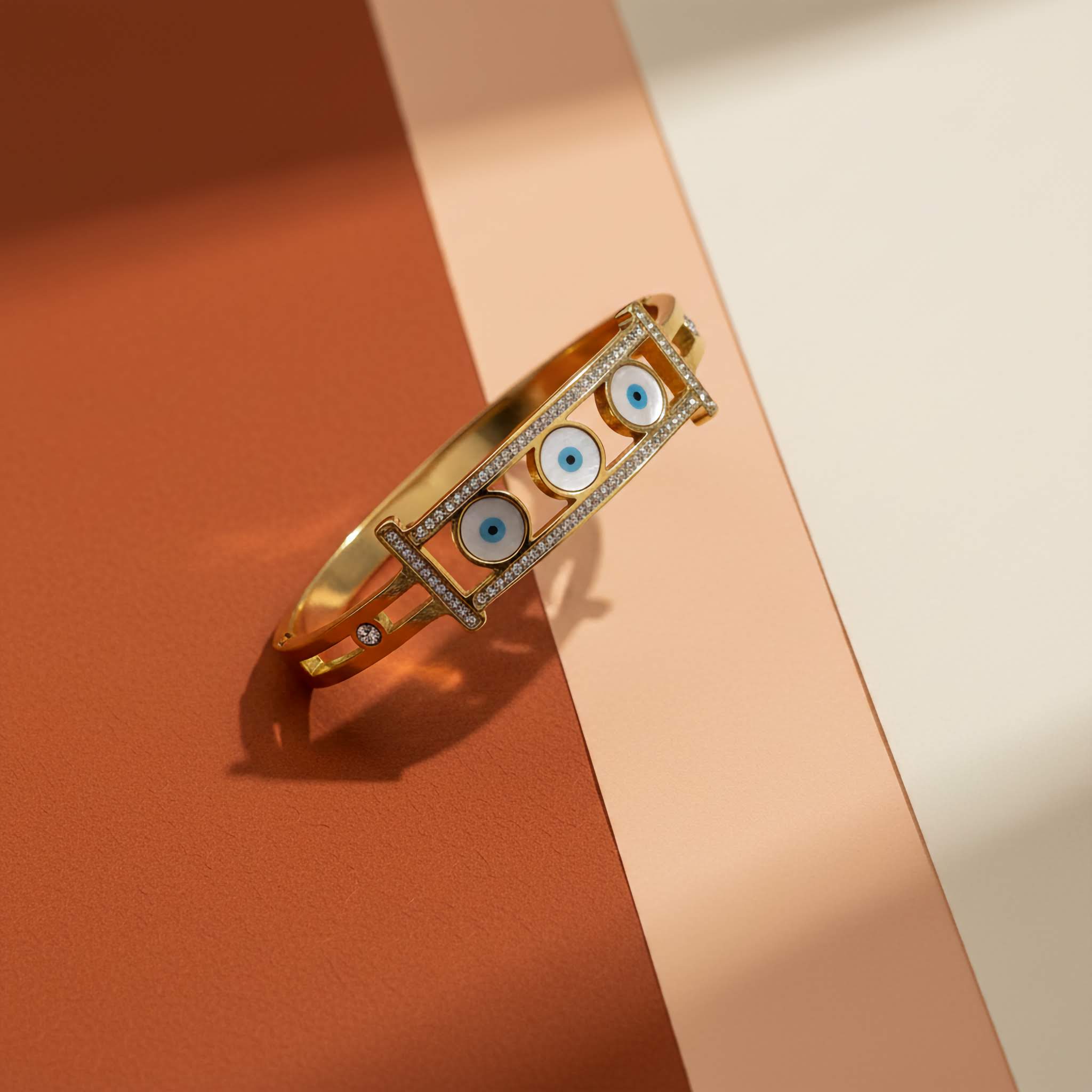 Gold plated bracelet with blue eye design on a two-tone background