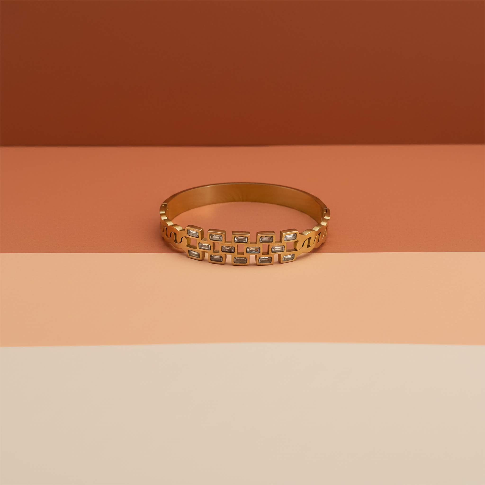 18k Gold plated bracelet with embedded zirconia stones on a two-tone peach and beige background