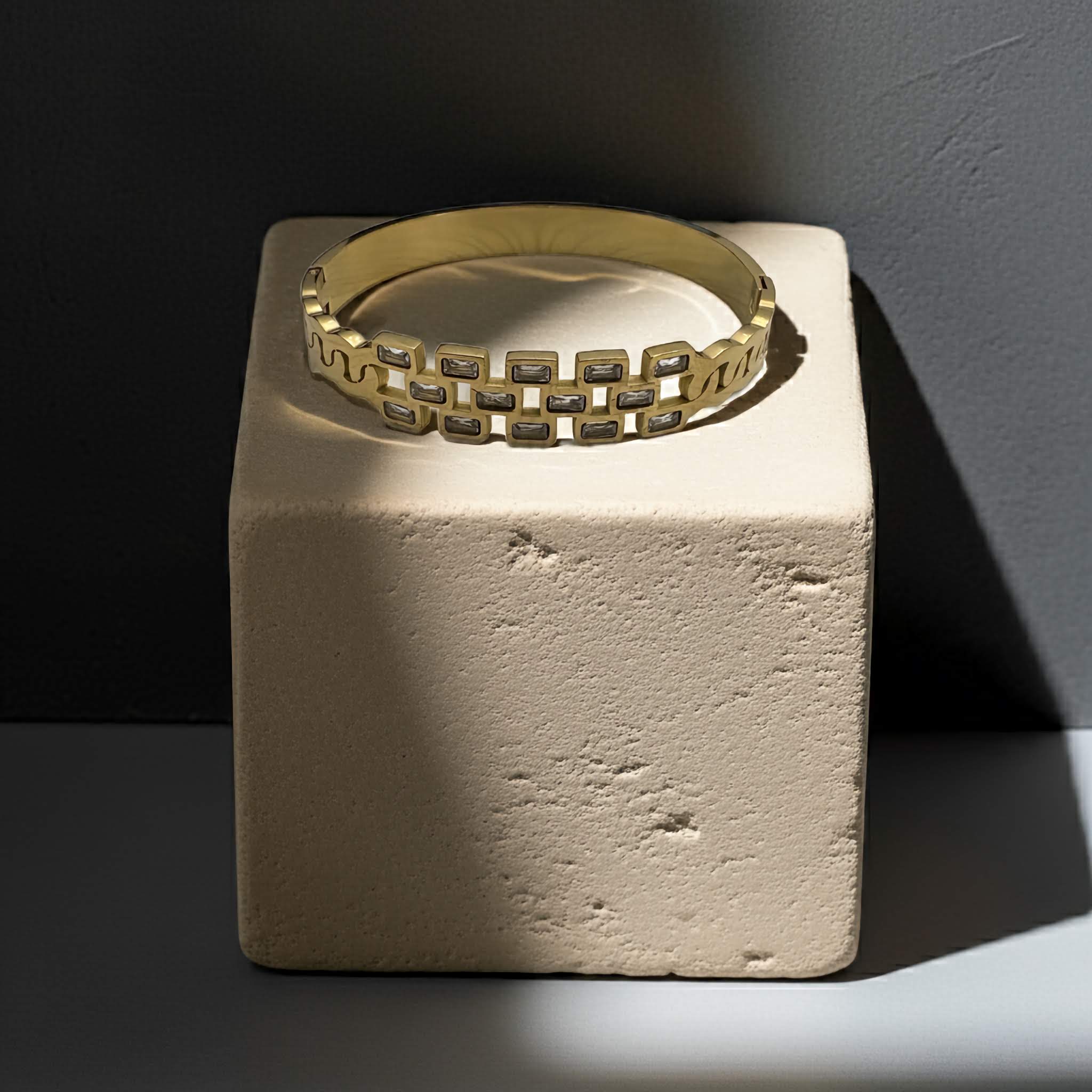 18k Gold plated bracelet with zirconia diamonds on a textured beige block against a dark background