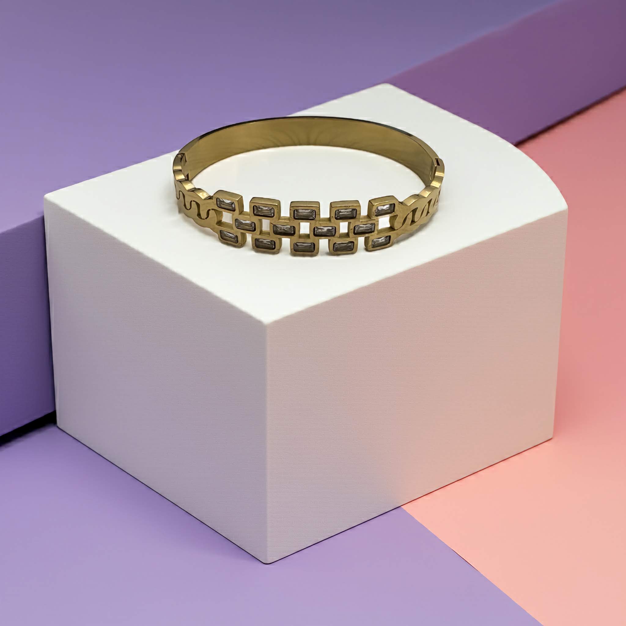 18k Gold plated chain bracelet on a white cube with a colorful background