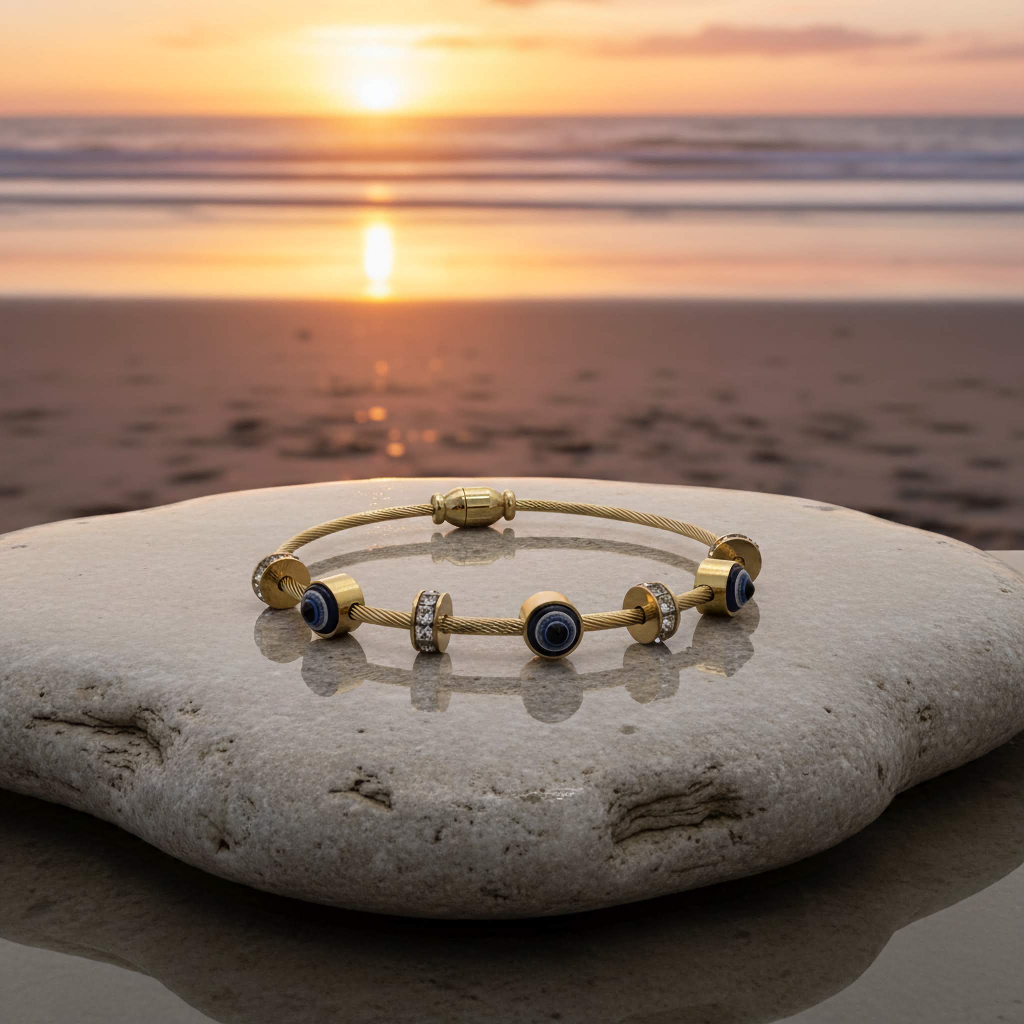 18k Gold plated evil eye bracelet with crystal stones on a rock by the sea at sunset