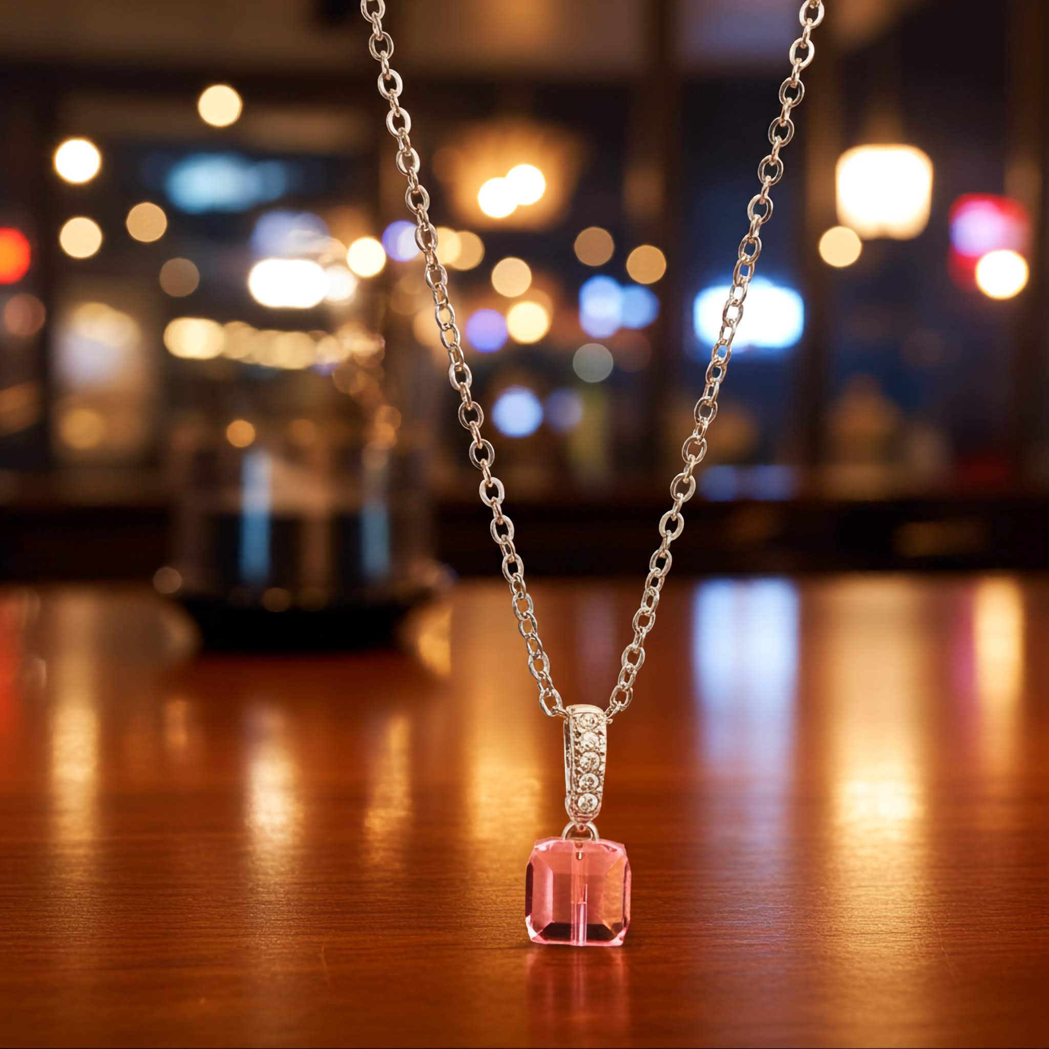 18k gold plated Necklace with a pink pendant on a wooden surface with blurred lights in the background