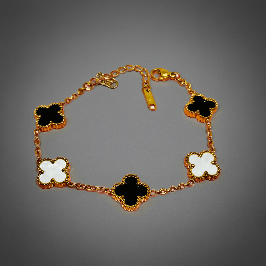 gold clover bracelet waterproof anti-tarnish with black and white clover-shaped charms on a gray background