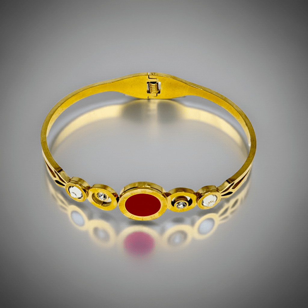 Gold bracelet with a red stone and small diamonds on a gray background