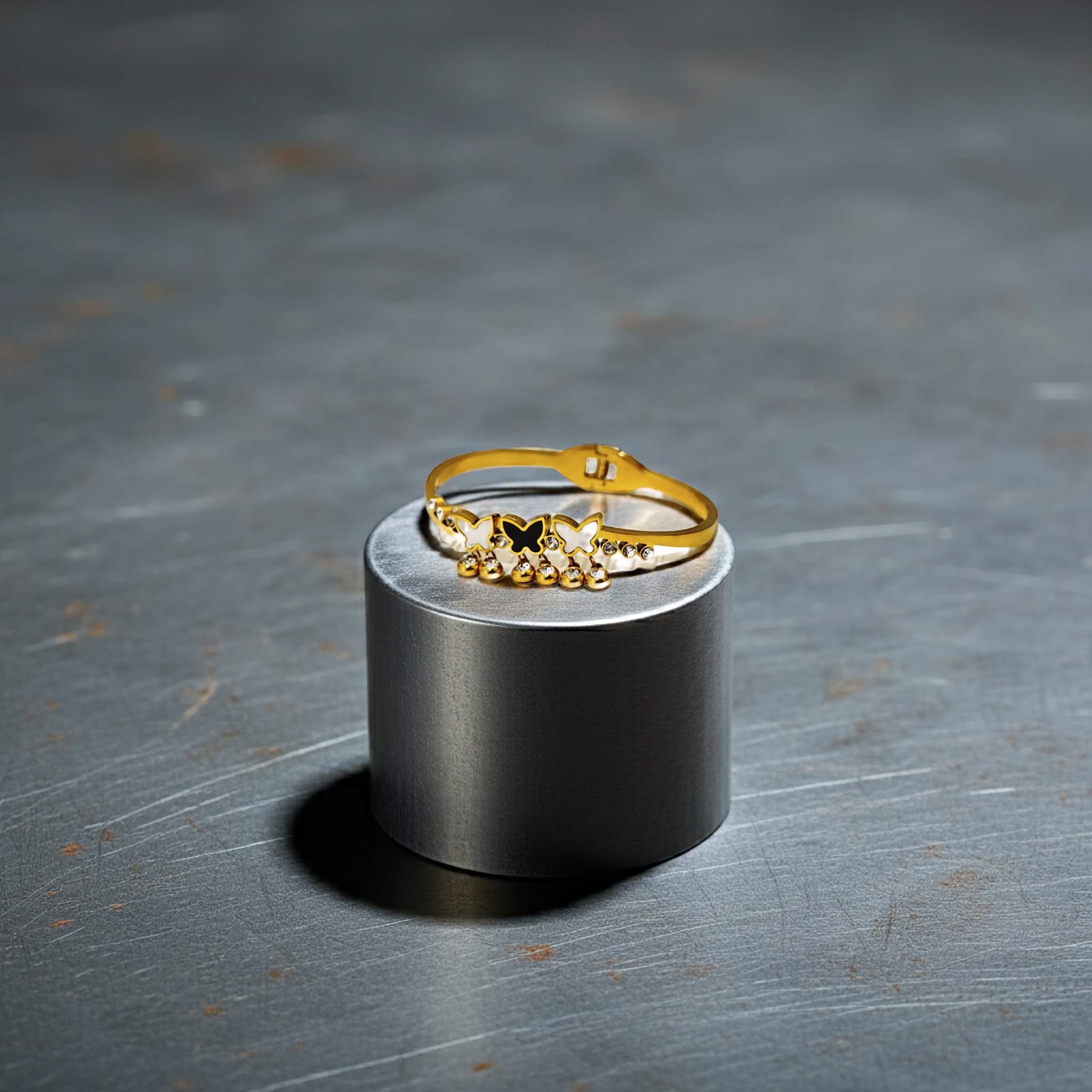 Gold bracelet with small stones on a metallic stand against a dark background