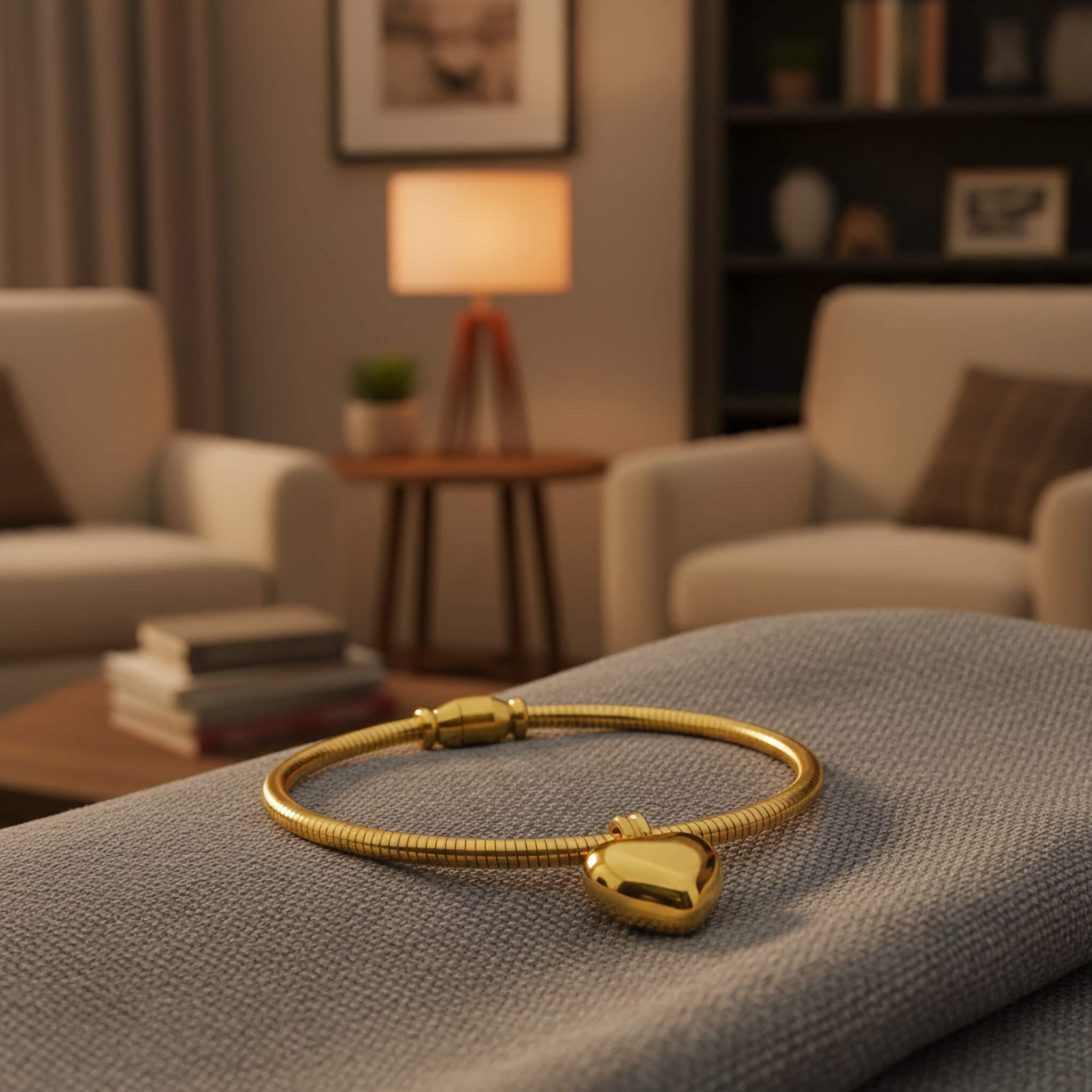 A Gold plated bracelet with a gold heart charm on a grey surface in a cozy living room.