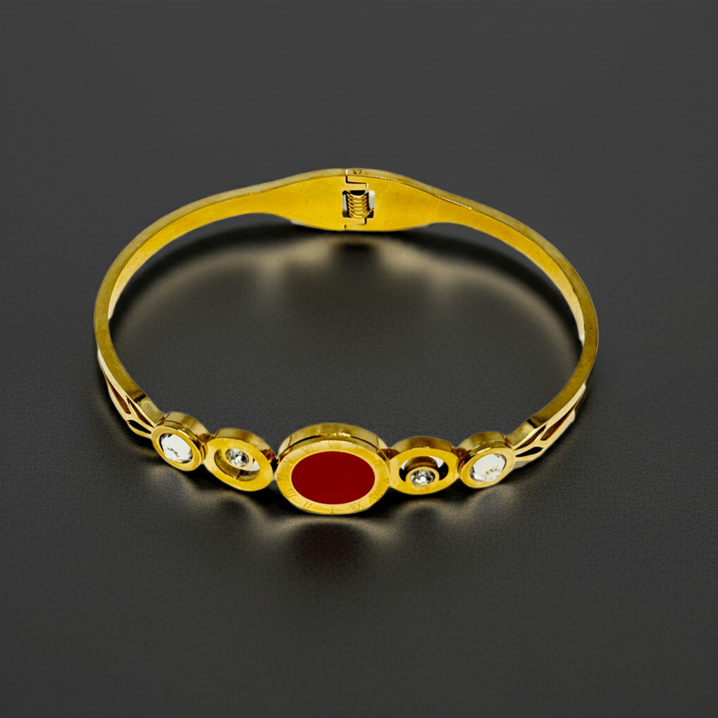 Gold bracelet with a red stone on a dark background