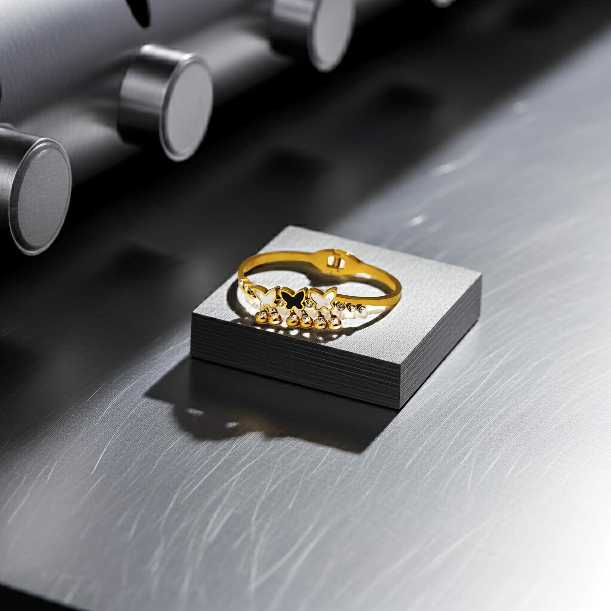 Gold bracelet on a black square platform with metallic background