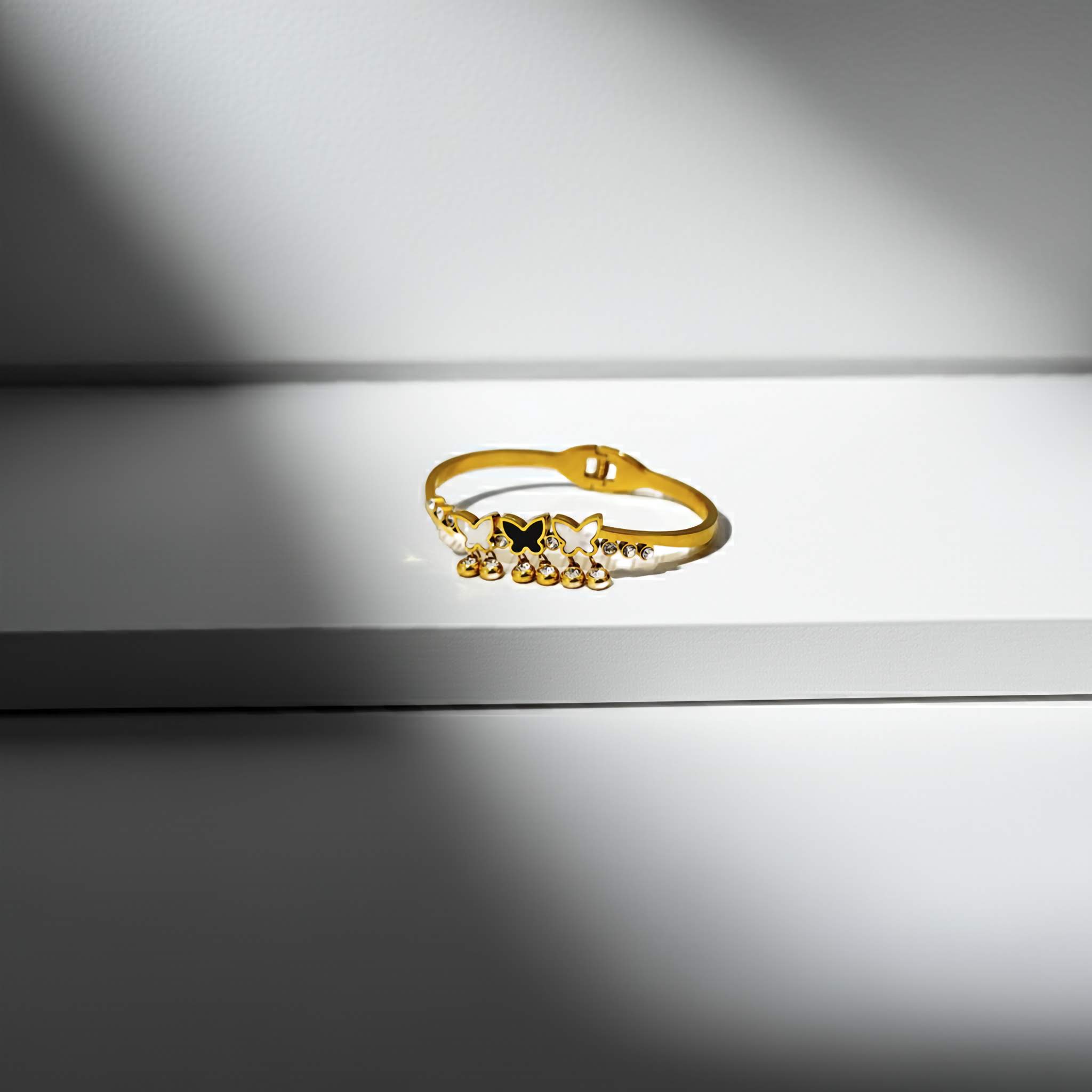 Gold bracelet with decorative elements on a reflective surface