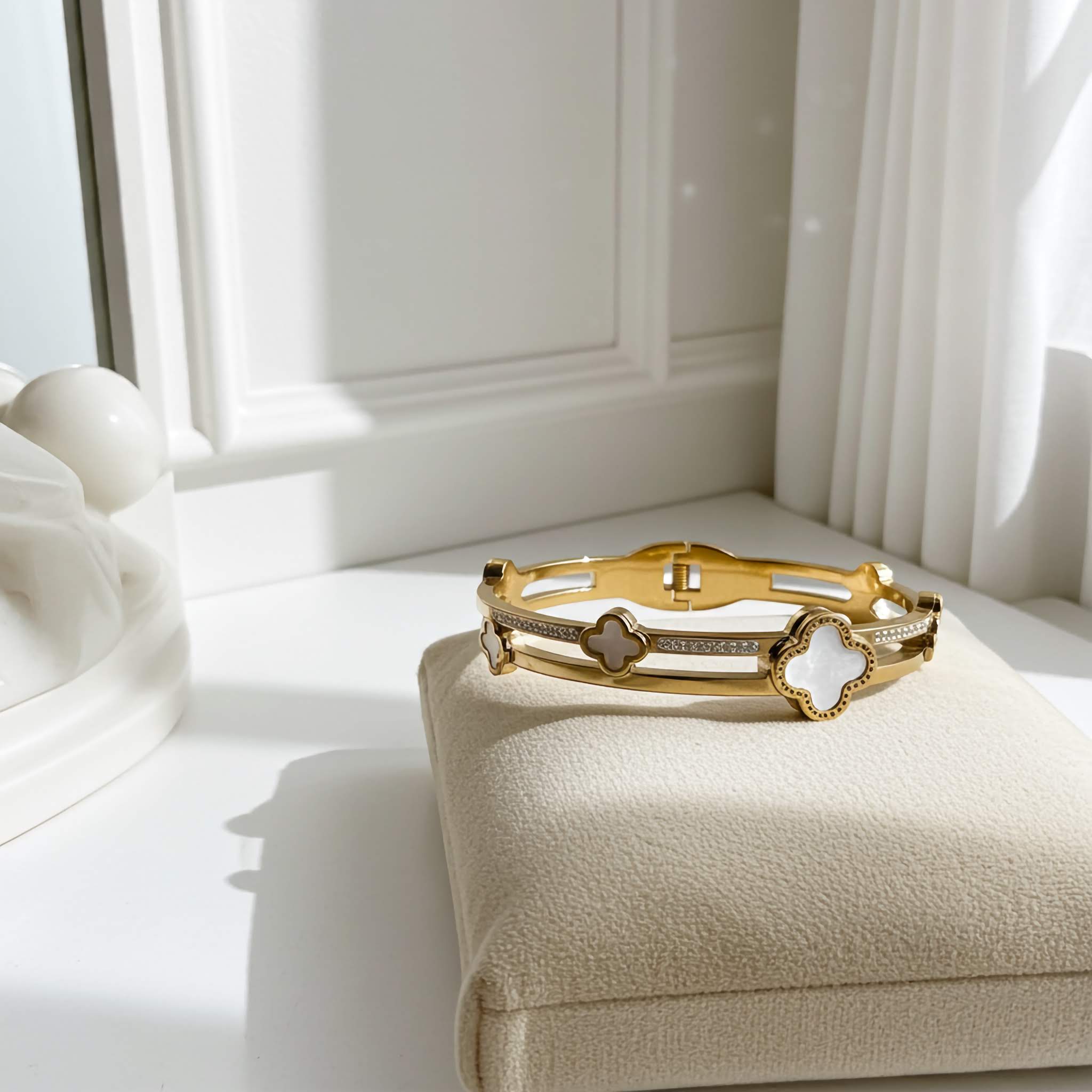 Gold bracelet with a clover design on a white surface