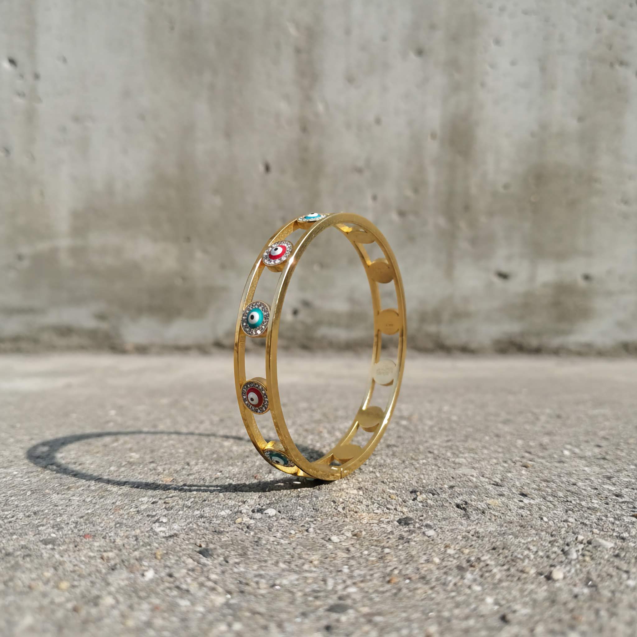 18k gold plated multicoloured evil eye bracelet in concrete background