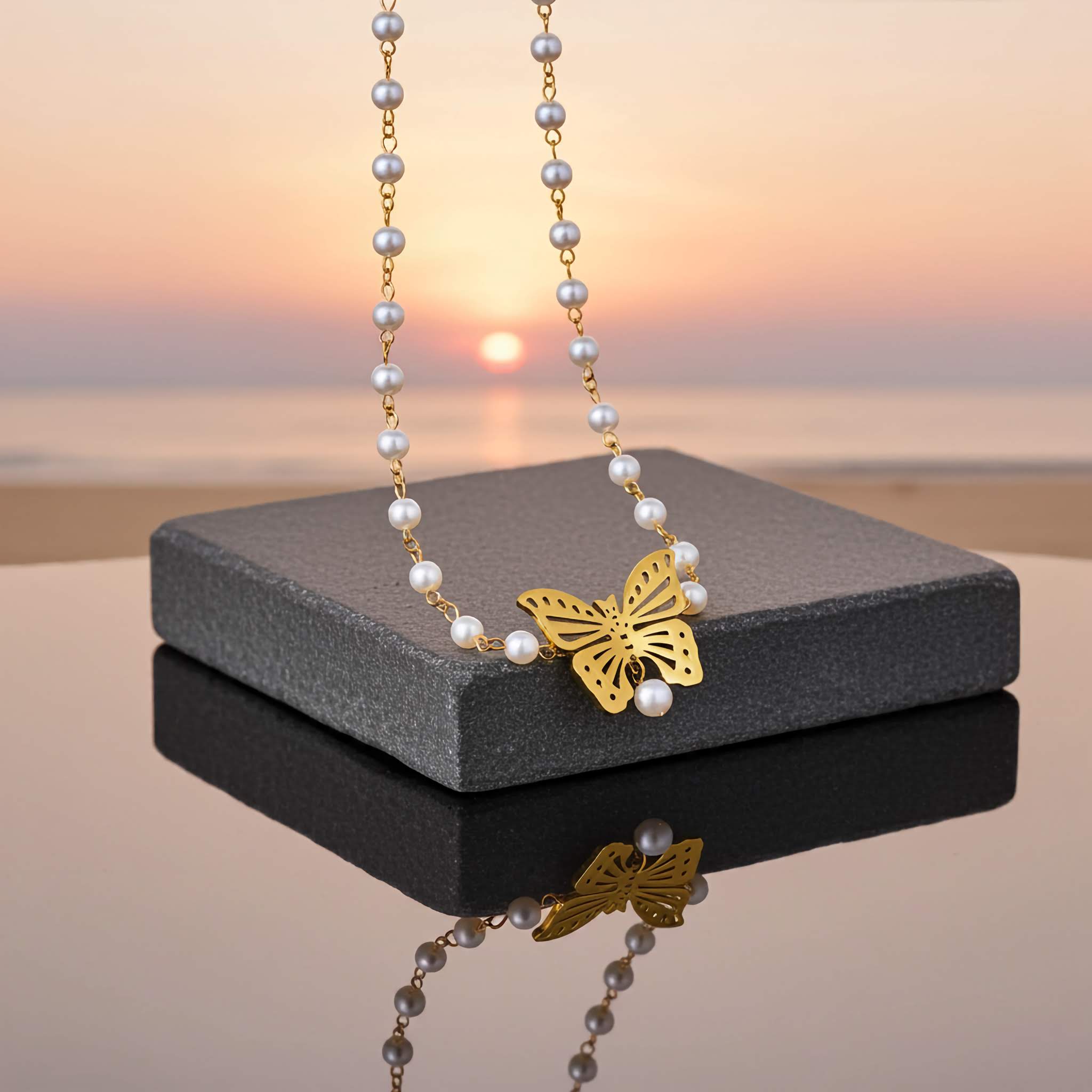 Necklace with a gold butterfly pendant on a gray stand against a sunset beach background