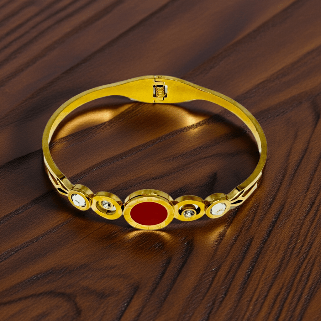 Gold bracelet with a red stone on a wooden surface