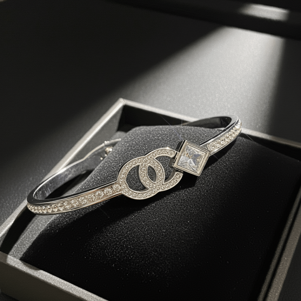 Silver bracelet with a logo on a black surface