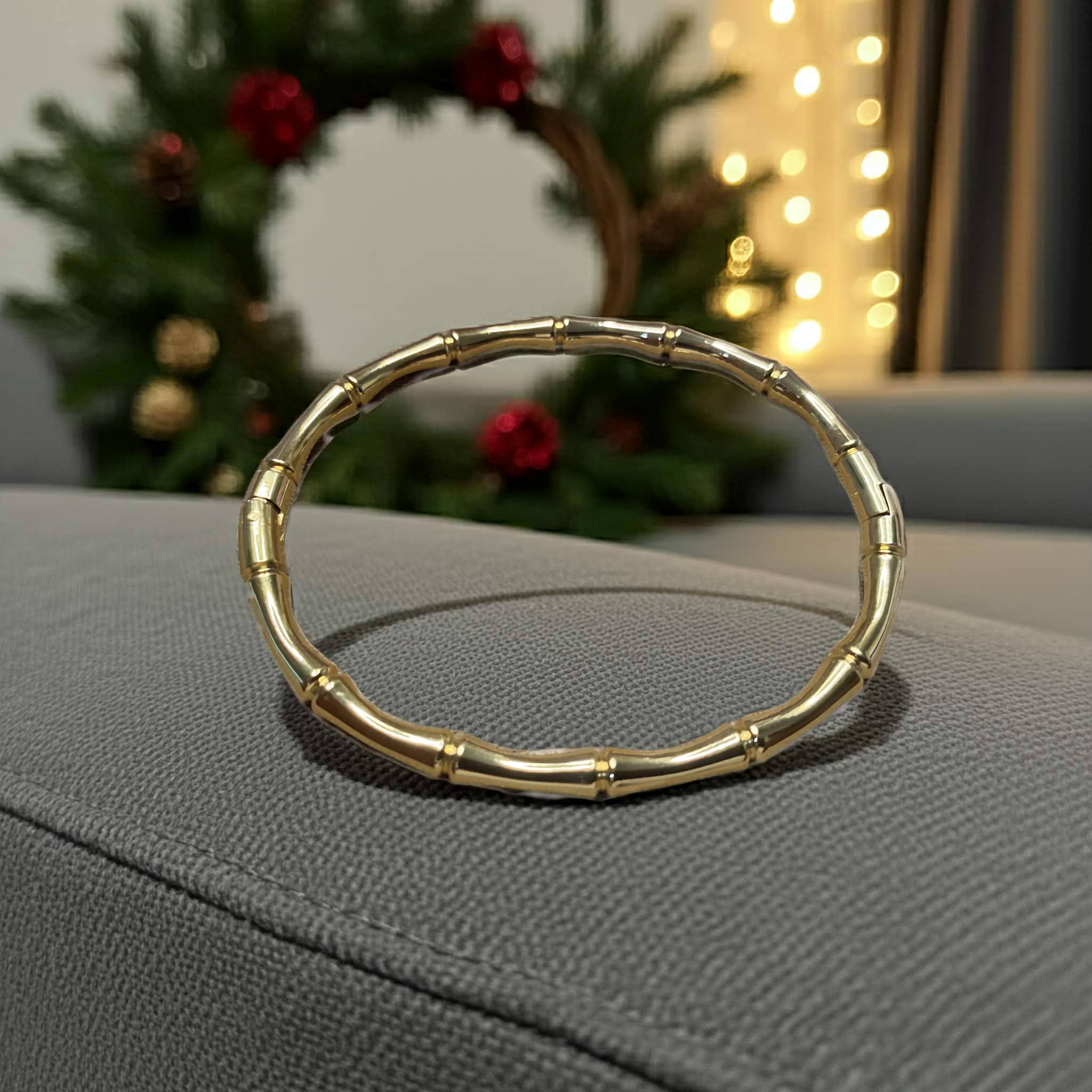 Bamboo-inspired Gold plated bracelet on a gray surface with a festive background