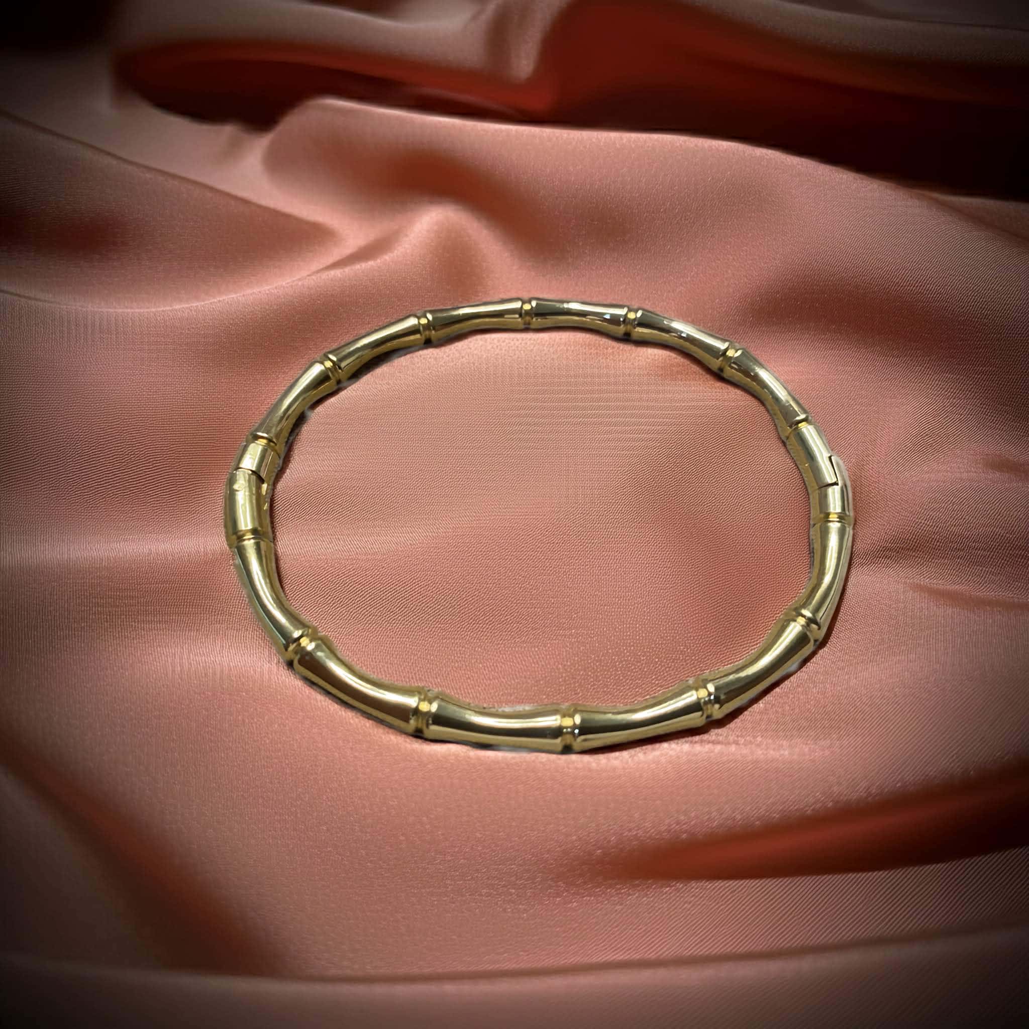 Bamboo-inspired Gold plated bracelet on a pink fabric background