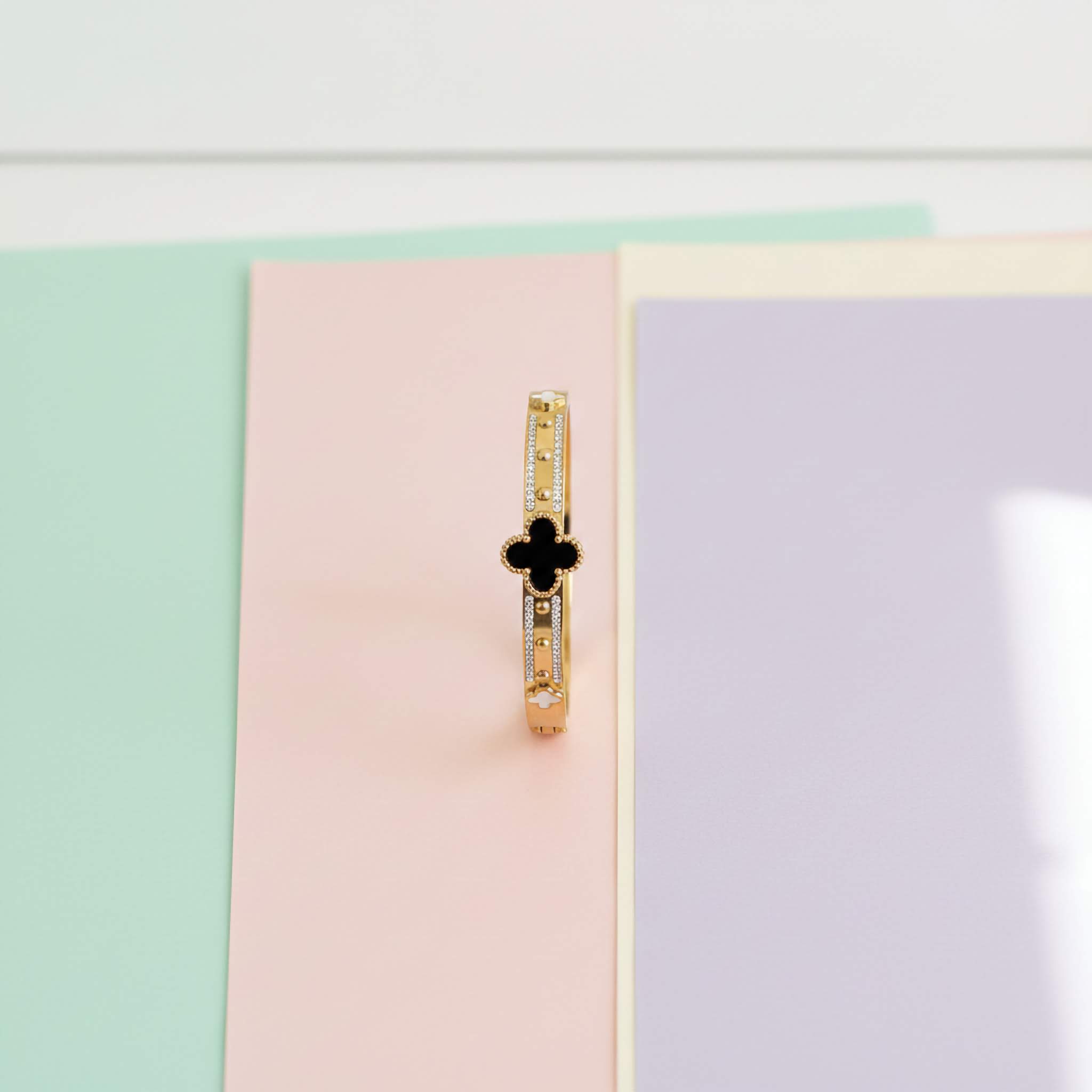 Black and white clover leaf bracelet on a multi-colour paper background