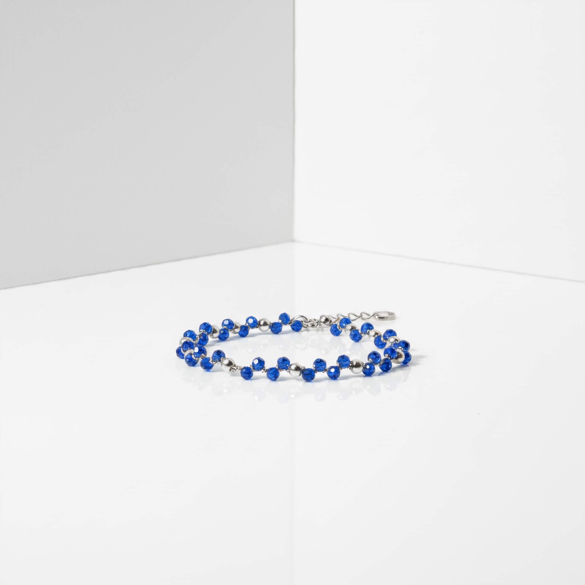 Blue beaded bracelet on a white surface with a gray background