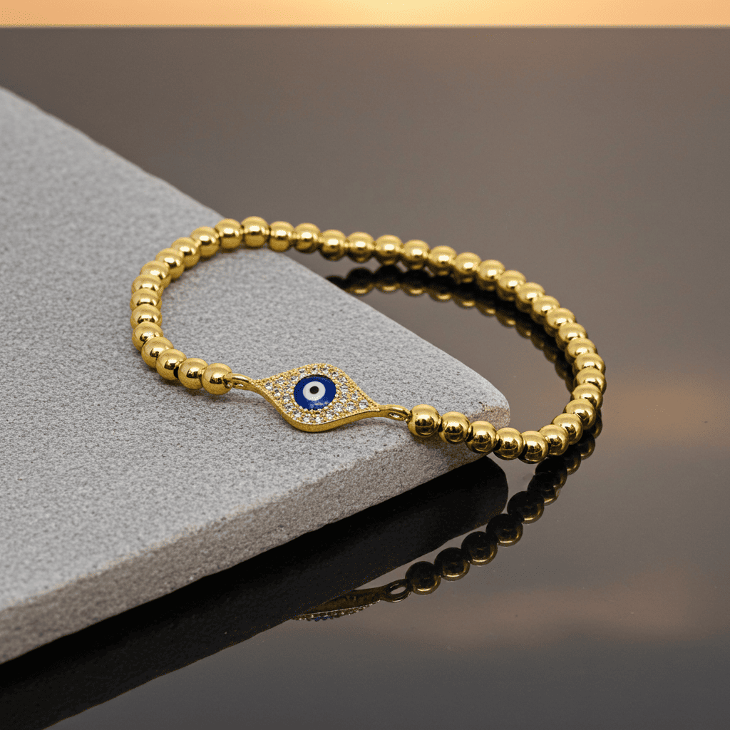 Stretchable Gold bracelet with a blue evil eye charm on a gray surface