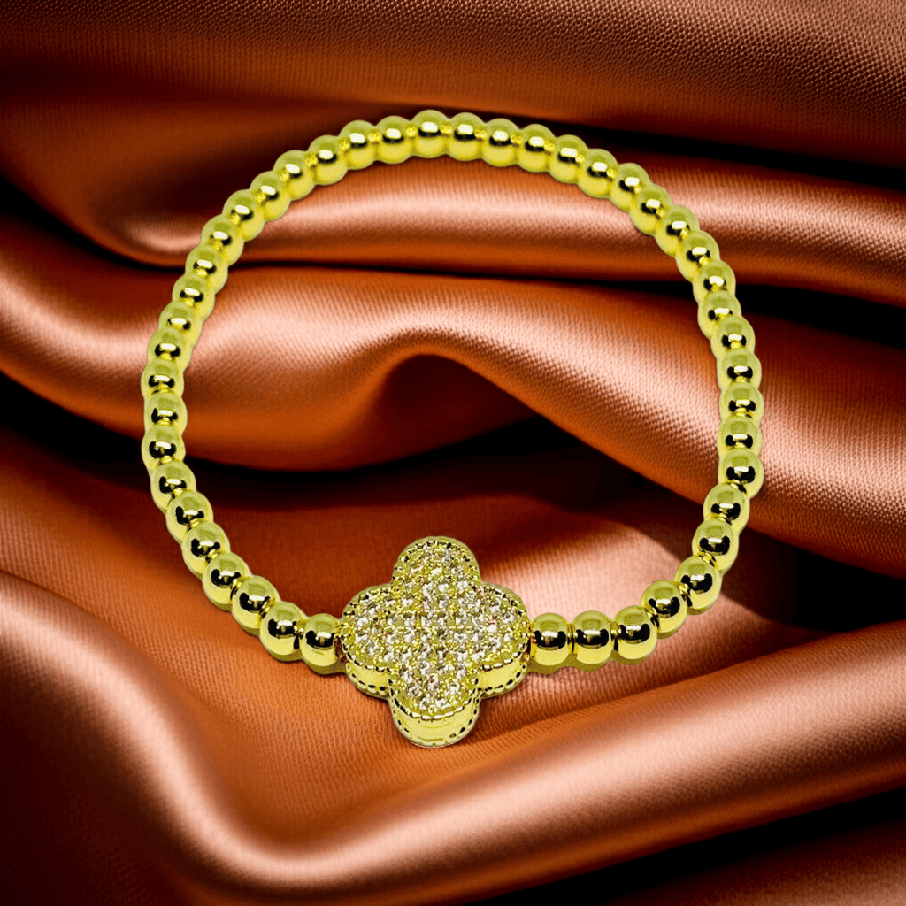 Shop Gold beaded slip-on bracelet with a clover on a satin background