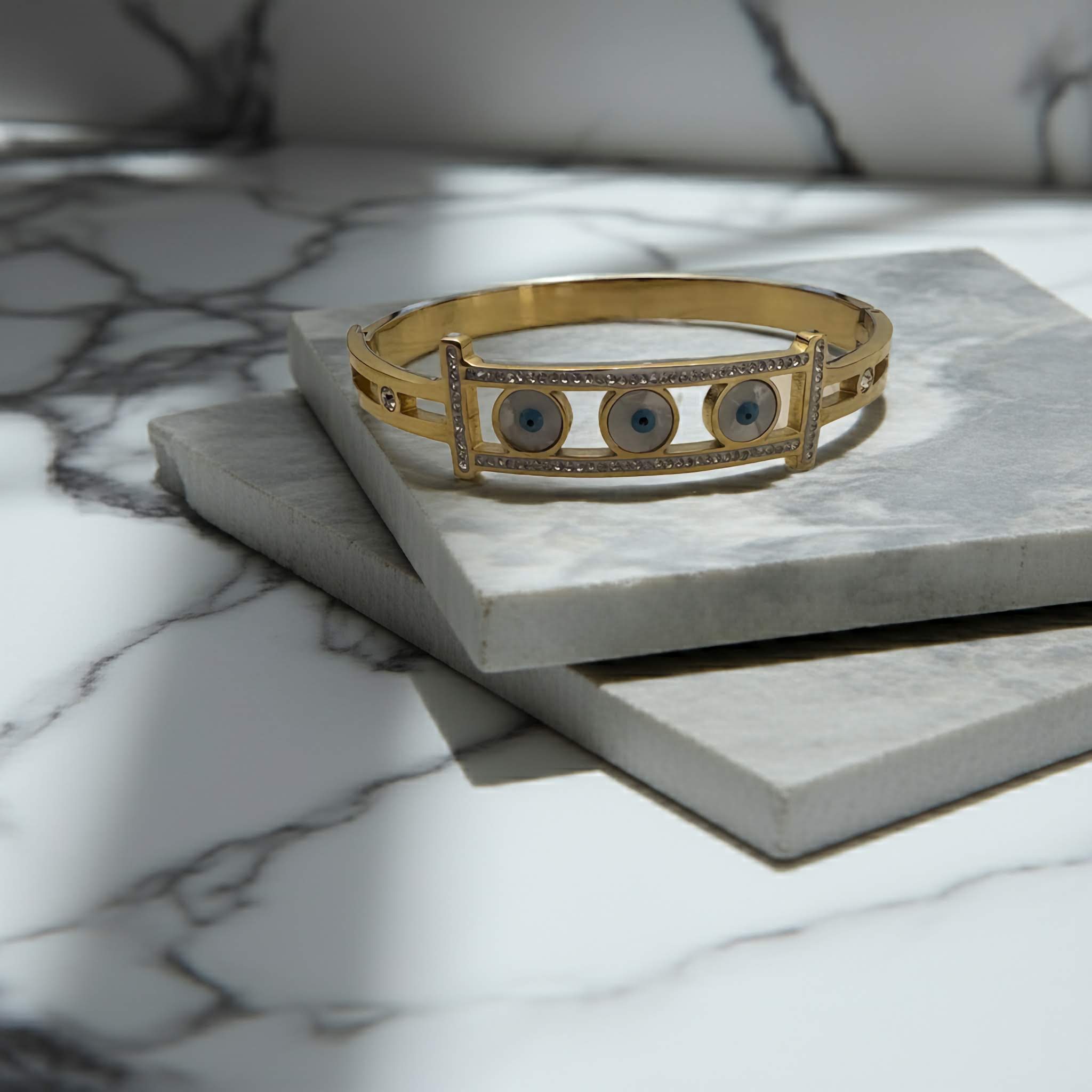 Evil Eye gold plated bangle on a marble surface