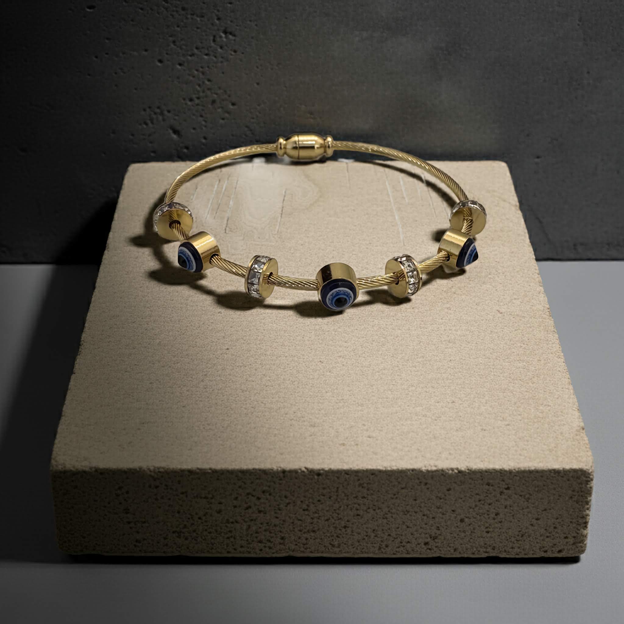 Evil Eye 18k Gold plated bracelet with blue and clear evil eye beads on a textured surface