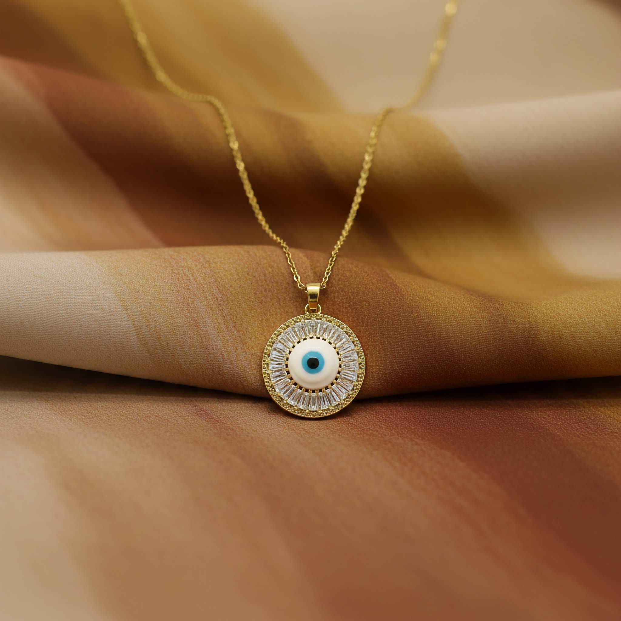 Gold necklace with an eye-shaped pendant on a brown fabric background