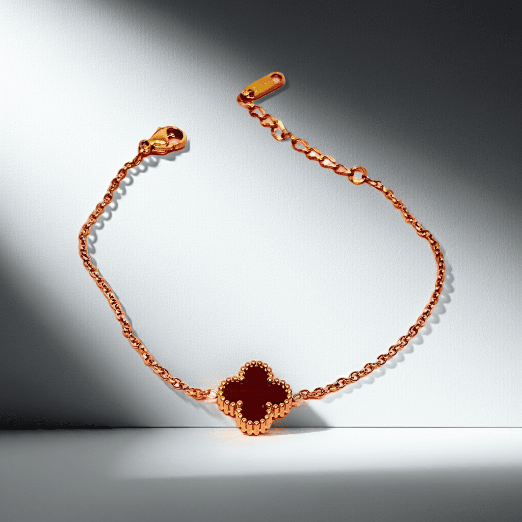 gold necklace with a black clover-shaped charm on a gradient background