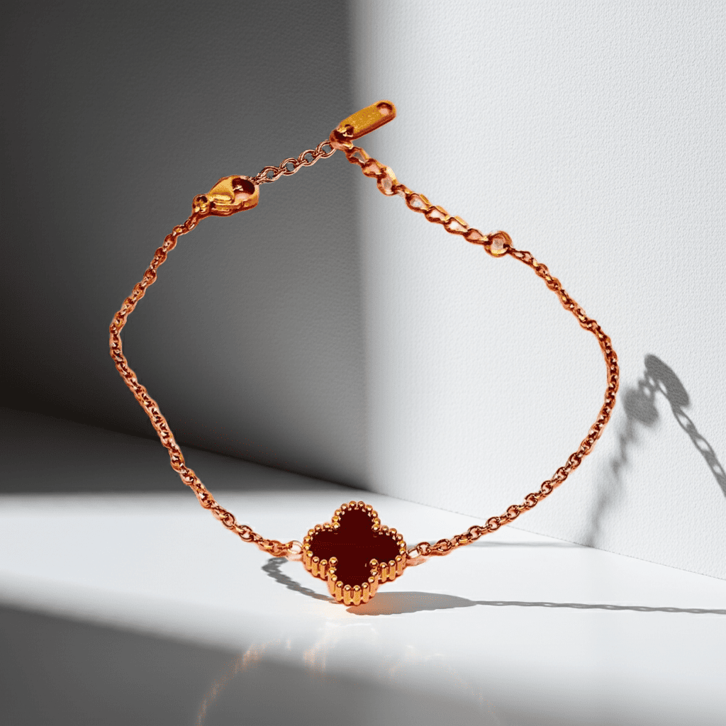 gold Necklace with a clover-shaped blck charm on a light background