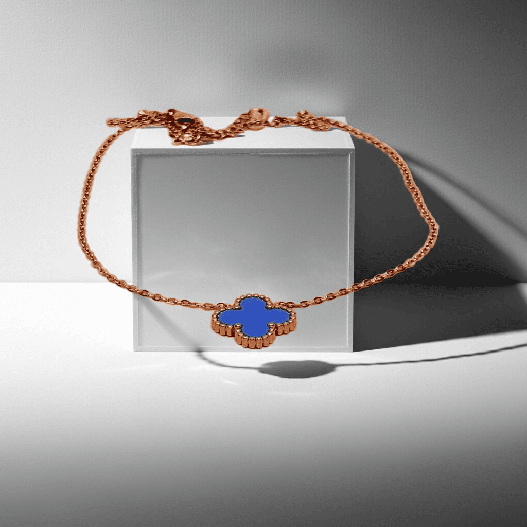 Gold Necklace with a blue clover-shaped pendant on a reflective surface