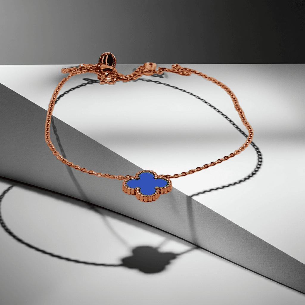 Gold necklace with a blue clover-shaped charm on a gray surface