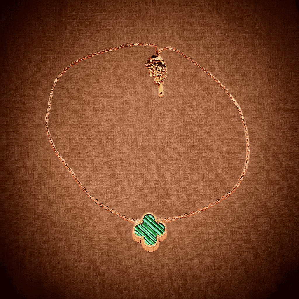 Gold necklace with a green clover pendant on a brown background