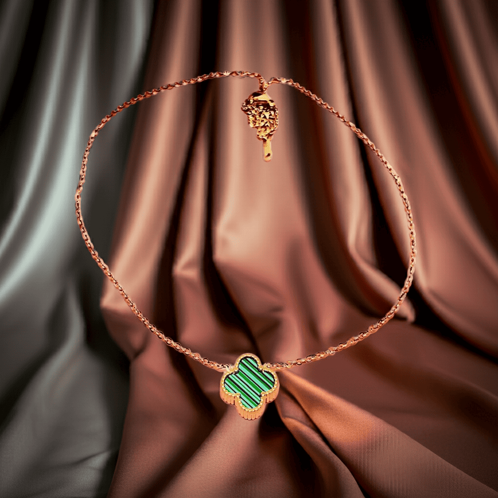 Gold Necklace with green stone clover pendant on brown fabric