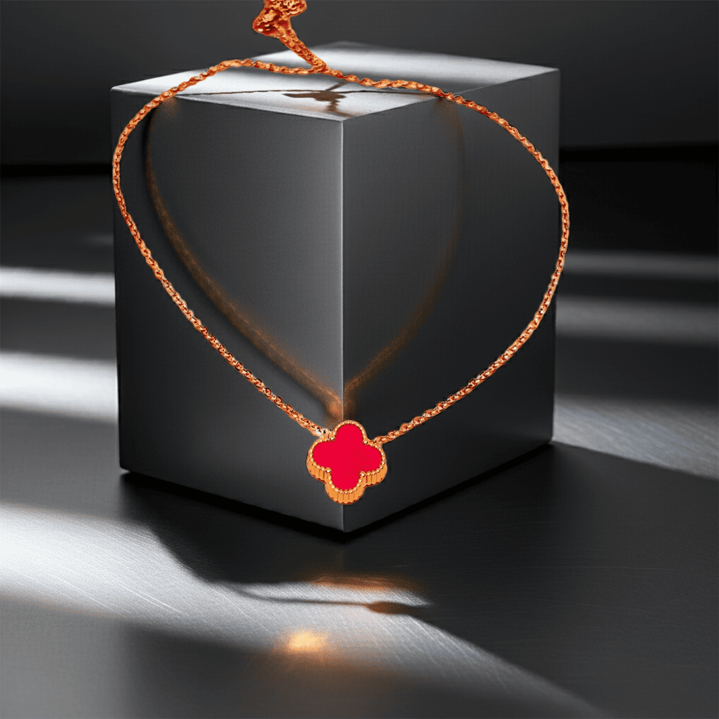 Gold Necklace with a red clover pendant on a black box