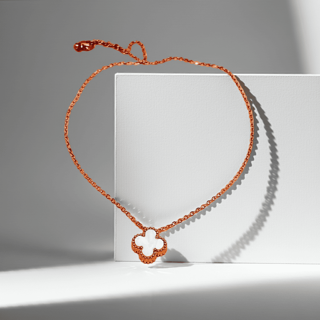 Gold necklace with a white clover pendant on a white surface