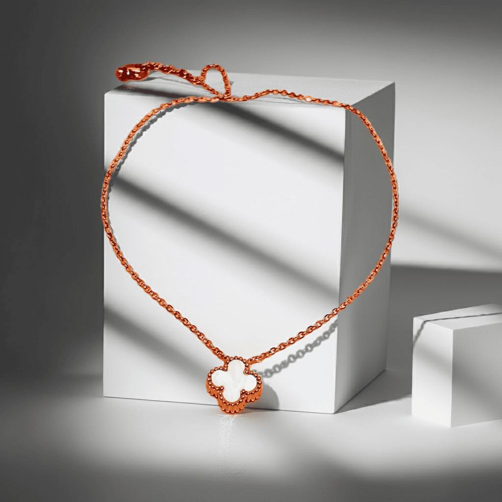 Gold Necklace with a unique white clover pendant on a white block against a gray background