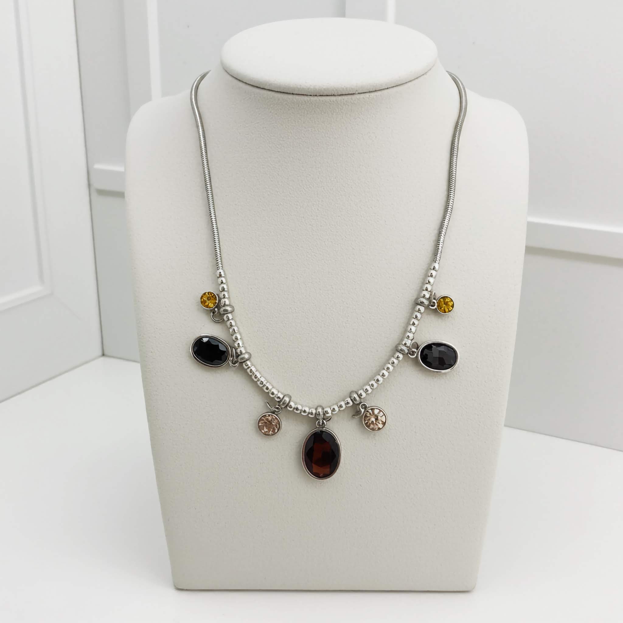 A Cheap $10 Silver plated Necklace with multicoloured beads on a white bust