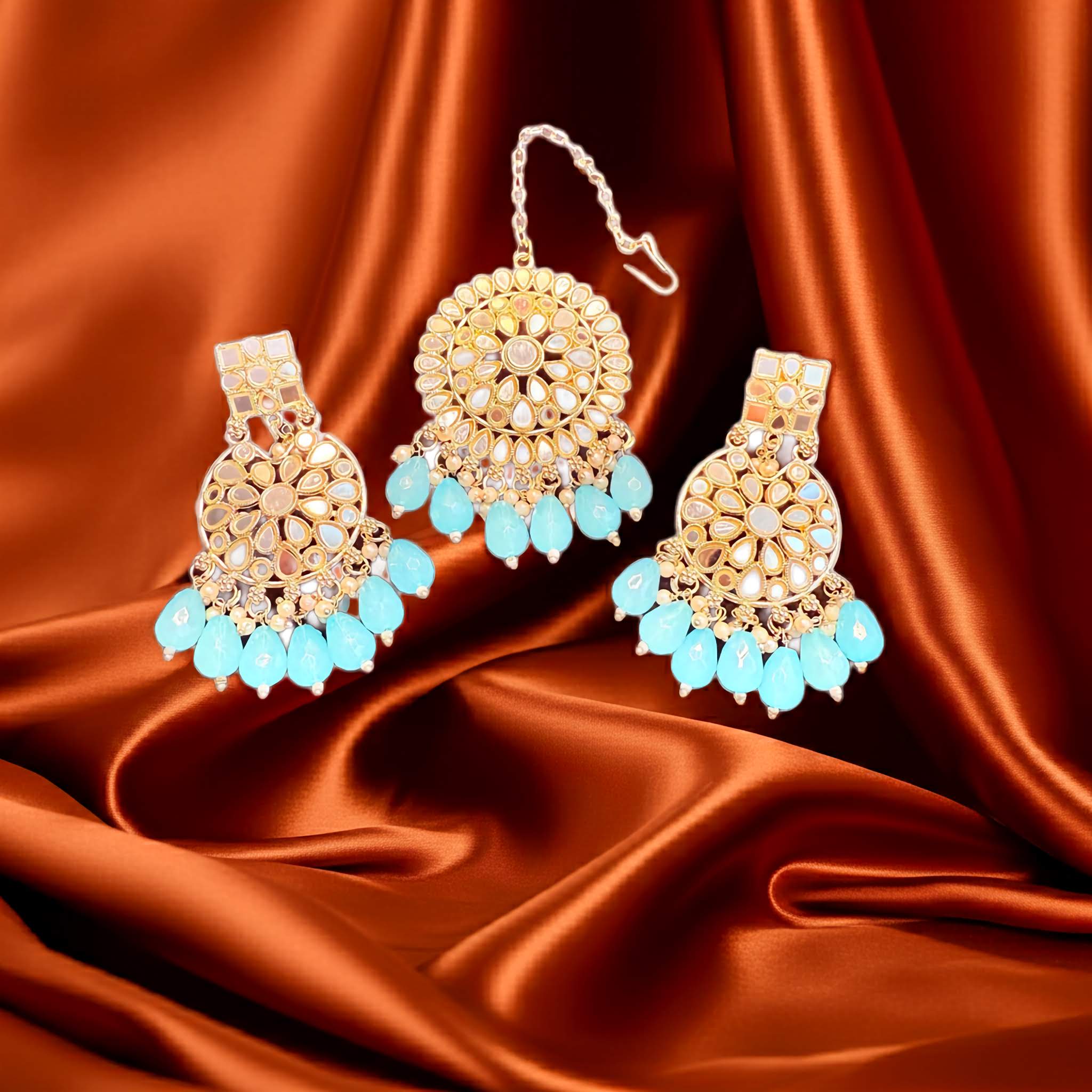 Gold and turquoise earrings on a satin fabric background